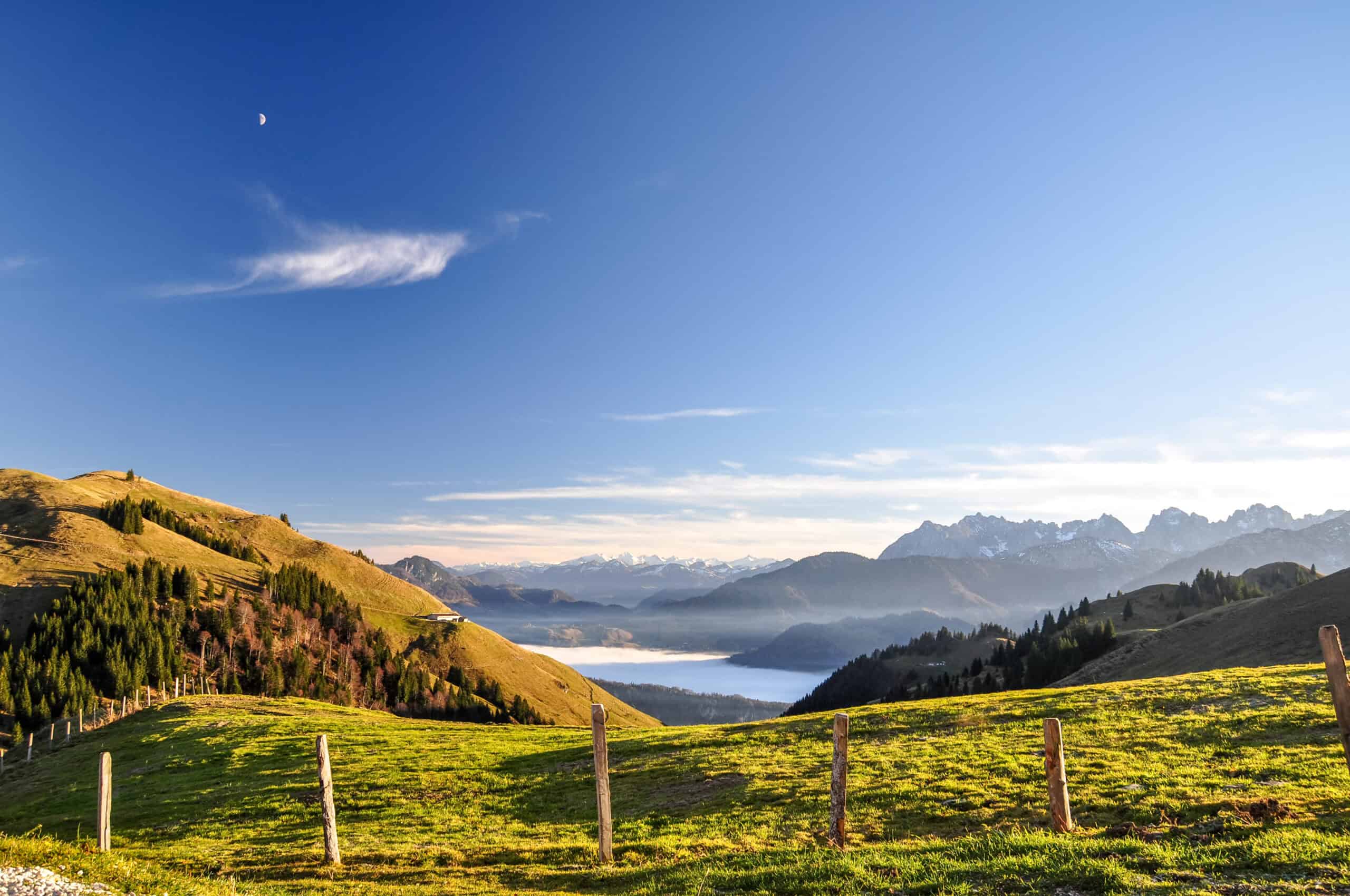Beautiful evening view near Wandberg mountain in the Chiemgau Alps mountain range in Austria. Tranquil scene with a fence, a fresh lawn and mountains in the background and fog in the lowland. Hausarzt Praxis Söchtenau - Leistung - Pflege