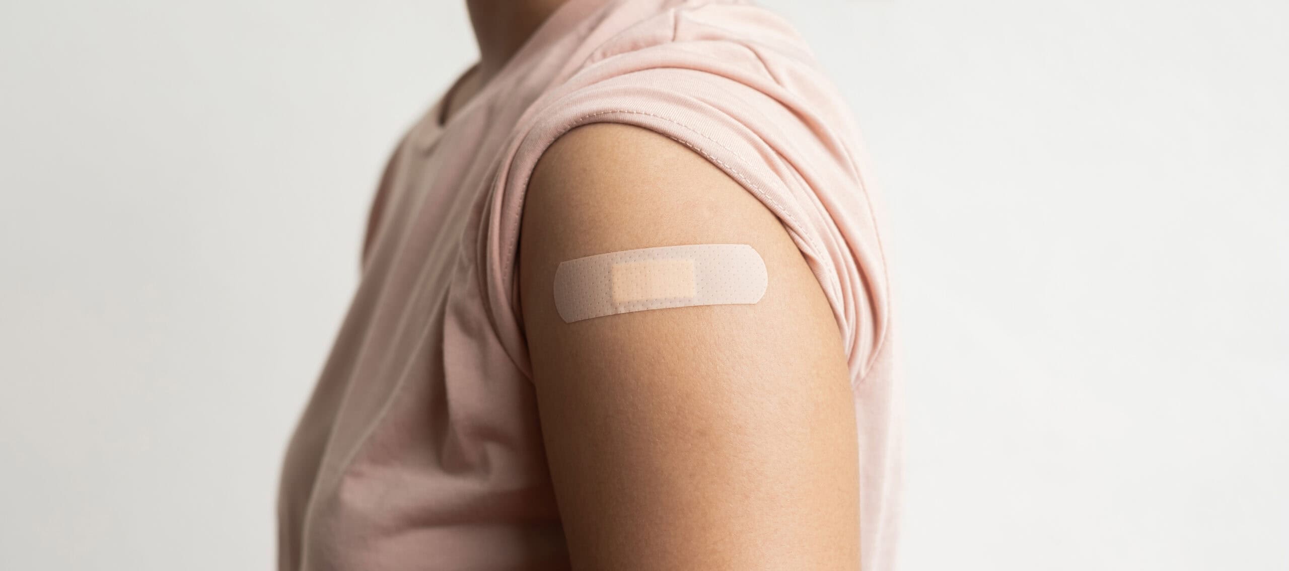 Asian woman shows plaster on her shoulder after being vaccinated against Covid-19. Coronavirus vaccination campaign concept Hausarzt Praxis Söchtenau - Leistung - Impfung